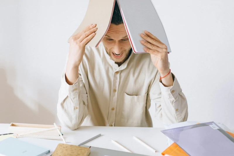 Mann verzweifelt über einem Stapel an Unterlagen, weil er keine wirksamen Stress-Bewältigungsstrategien hat
