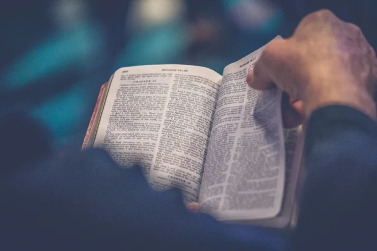 Mann liest in einem Buch, das wie eine Bibel aussieht. Metapher dafür, dass unsere Glaubenssätze uns anleiten, wie es sonst auch der Glaube tut.