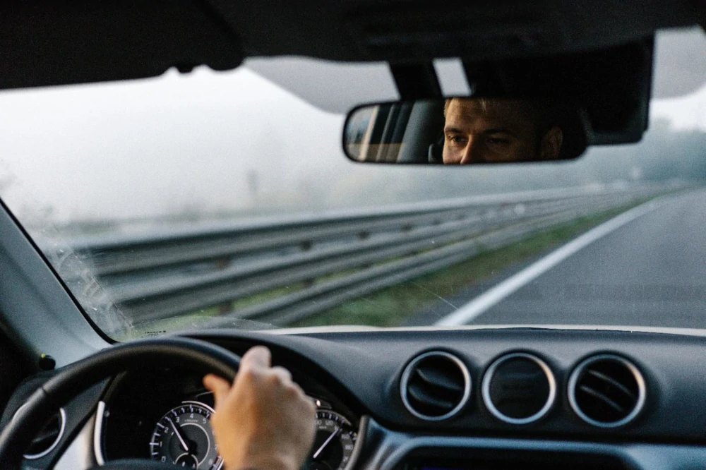 Blick über die Schulter eines Autofahrers auf die Straße.